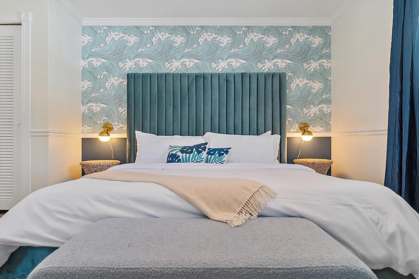 Airbnb bedroom with blue wave wallpaper and a teal channel-tufted headboard