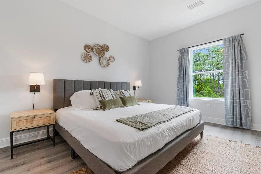 Minimal Airbnb bedroom with a low gray bed, small nightstands, and garden doors