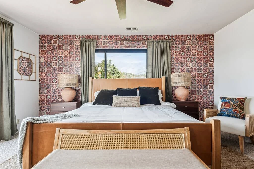 Airbnb bedroom with patterned wallpaper, carved wood furniture, and rust-colored accents